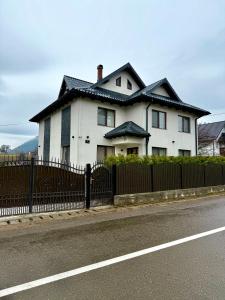 a white house with a fence on the side of the road at Transrarau Lodge in Pojorîta