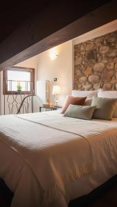 a bedroom with a large white bed with a stone wall at Piccola casa vacanze - Small vacation house in Porto Valtravaglia