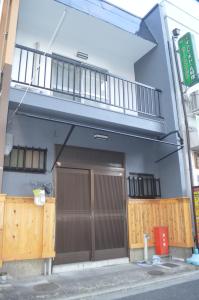ein Gebäude mit einer Tür und einem Balkon in der Unterkunft 折り鶴 Orizuru Guest House in Kyoto