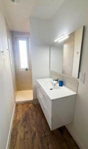 Un baño blanco con lavabo y espejo. en Parenthèse à l'Oasis, en Ploërmel