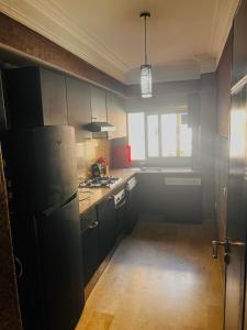 uma cozinha com armários pretos e um frigorífico em Corniche Apartments em Casablanca