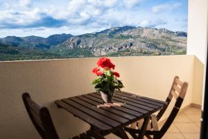 a wooden table with a vase of flowers on a balcony at APARTAMENTOS SERRELLA - Rural Guadalest in Benimantell