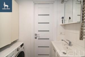 a white bathroom with a sink and a washing machine at Loftas Dumu fabrikas in Vilnius
