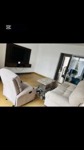 a living room with two chairs and a flat screen tv at Shalom Apartment in Lusaka