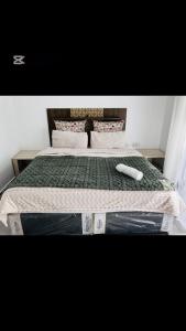 a bed with a green comforter and a white object on it at Shalom Apartment in Lusaka
