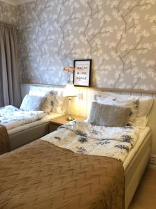 a bedroom with two beds and a wall covered in wallpaper at Haus Anna in Rauma