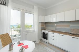 a kitchen with white cabinets and a table and a window at Peraia beachfront apartment in Perea