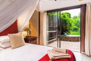 a bedroom with a bed and a sliding glass door at Lodge Forest Suite in Hluhluwe