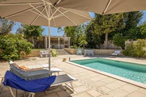 a pool with an umbrella and a chair and a table with an umbrella at Villa Enea in Poggiardo