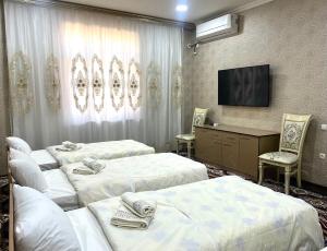 a hotel room with three beds and a television at Hostel Marshal in Termiz