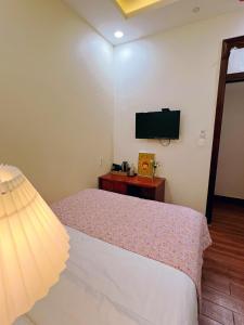 CaRa Hotel Đà Lạt في دالات: غرفة نوم مع سرير وتلفزيون بشاشة مسطحة