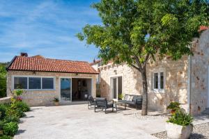 een stenen huis met een patio en een boom bij Villa Olim Civitas in Škrip