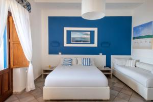 a bedroom with a white bed and a couch at Da Nino sul mare Filicudi in Filicudi