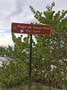 a brown sign on a pole in front of a bush at Pacifique un Bungalow charmant pour deux, entre mer et nature in Saint-Louis