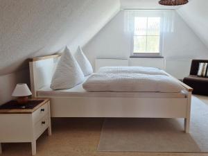 a white bed with white pillows and a window at Ferienhaus Hummel-Nest in Laußnitz