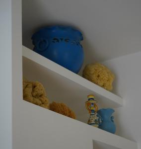 a shelf with a blue vase and some teddy bears at Nicuzza in Gela