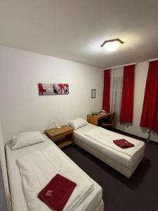 two beds in a hotel room with red curtains at Hotel Nassauer Hof Frankfurt in Frankfurt/Main