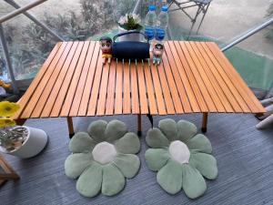 a wooden table with two dolls and flowers on the floor at แพนด้าแคมปิ้งเขาใหญ่ in Ban Khanong Phra Klang (1)