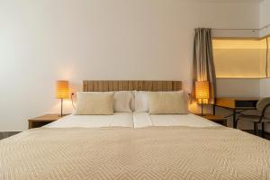 a bedroom with a large bed with two lamps at Musart Entre Artes in Jerez de la Frontera