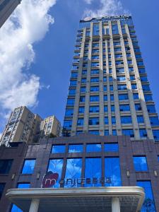 een hoog gebouw met een blauwe lucht op de achtergrond bij Manju Hotel Fuquan People's Square Branch in Fuquan