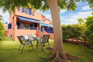 a table and chairs under a tree in front of a building at Villa Flamboyán Meloneras in Meloneras