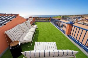 a balcony with white chairs and a green lawn at Villa Flamboyán Meloneras in Meloneras