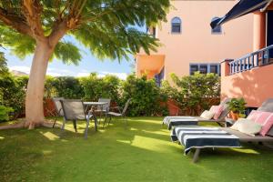 a yard with chairs and a table and a tree at Villa Flamboyán Meloneras in Meloneras