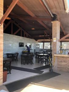 a man standing at tables in a restaurant with wooden ceilings at Pipa's Bay Apt 104 - PÉ NA AREIA in Pipa