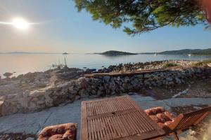 a group of birds sitting on a stone wall next to a lake at Secluded fisherman's cottage Krknata, Dugi otok - 8150 in Zaglav