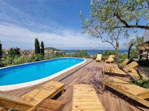 カリにあるFamily-friendly apartments with swimming pool Kali, Ugljan - 14116の木製の椅子と海の景色が見えるプール
