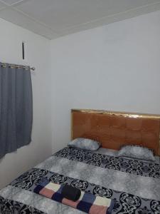 une chambre avec un lit avec une tête de lit en bois dans l'établissement Bukit Lawang Joint Trekking Loge & Transport, à Bukit Lawang