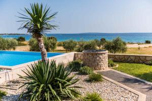 Un complejo con una palmera y una piscina. en Seaside luxury villa with a swimming pool Cove Mihovilje, Pag - 16124, en Novalja