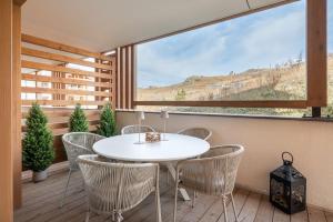于埃Apartment Vira Alpe d'Huez - by EMERALD STAY的阳台配有白色的桌椅和大窗户。