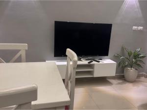 a living room with a tv and a white table with a chair at Alma & Thiago House in Sharm El Sheikh