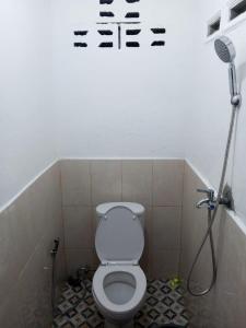 une salle de bain avec des toilettes avec des inscriptions sur le mur dans l'établissement Bukit Lawang Joint Trekking Loge & Transport, à Bukit Lawang