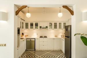 a kitchen with white cabinets and a black refrigerator at La Selva - 4BHK Luxury Villa in Assagao with Private Pool near Cafés & Soro Pub in Assagao +104 photos