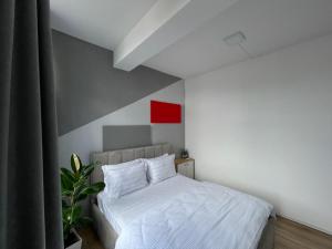 a bedroom with a white bed and a red wall at I&O Loft360 in Shkodër