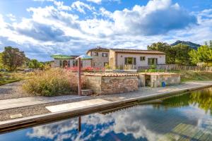 ein Haus mit einem Teich davor in der Unterkunft Gîte avec piscine de 25 m et spa in Saint-Mathieu-de-Tréviers
