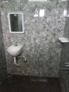 La salle de bains est pourvue d'un lavabo et d'un miroir sur un mur en pierre. dans l'établissement Msquare guest house, à Godāvari 1 autre photo