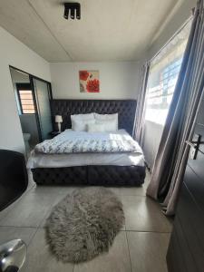 a bedroom with a bed with a furry rug on the floor at Home away from home in Midrand