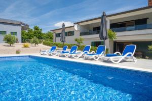 a pool with chairs and umbrellas next to a house at Luxury villa with a swimming pool Trget, Rasa - 23420 in Trget