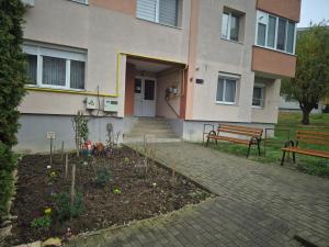 奥多尔黑塞库耶斯克Tranzit apartman 3的一栋建筑，前面有长椅和花园。