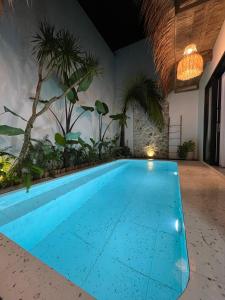 an empty swimming pool in a room with palm trees at Djeladjah Villa in Ngingas +13 photos