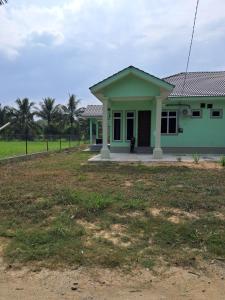 a green house with a person standing in the yard at Homestay Kubang Kerian, Kota Bharu in Kota Bharu