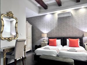 a bedroom with a bed with orange pillows and a mirror at Casa Birmula Boutique Hotel in Cospicua +169 photos
