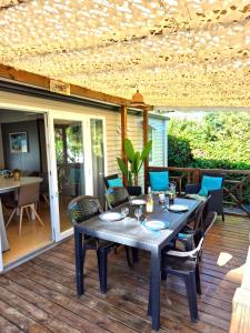 a dining table and chairs on a deck with a table and chairs at HappyMobilhome Argelès-sur-mer -plage à 500m- Camping 4 étoiles Del Mar in Argelès-sur-Mer
