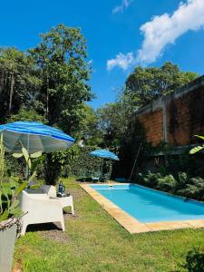 ein Pool mit zwei Sonnenschirmen und zwei Stühlen in der Unterkunft Tuchita House en Cataratas con piscina compartida parrilla, cochera in Puerto Iguazú