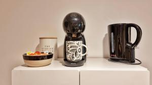 een koffiezetapparaat en een kopje op een witte plank bij Gîte Renaud et Lauren - Terrace - Horbourg-Wihr in Horbourg