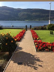 a walkway with flowers in a park next to a body of water at Fassfern Guesthouse in Fort William