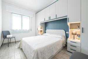 een witte slaapkamer met een groot bed en een stoel bij Sole e Mare Buggerru - Appartamento in Buggerru